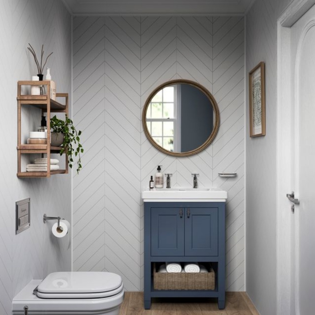 Lifestyle image of the Showerwall Laminate Snow White 2400mm x 600mm Chevron Tile Effect Wall Panel - SWT16 installed behind a blue vanity unit with basin and round mirror